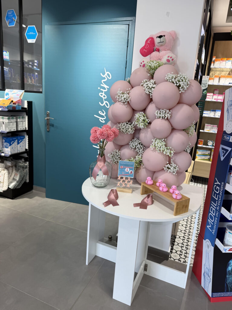 Le stand Octobre Rose de la pharmacie de Levens : arche de ballons roses, canards et rubans