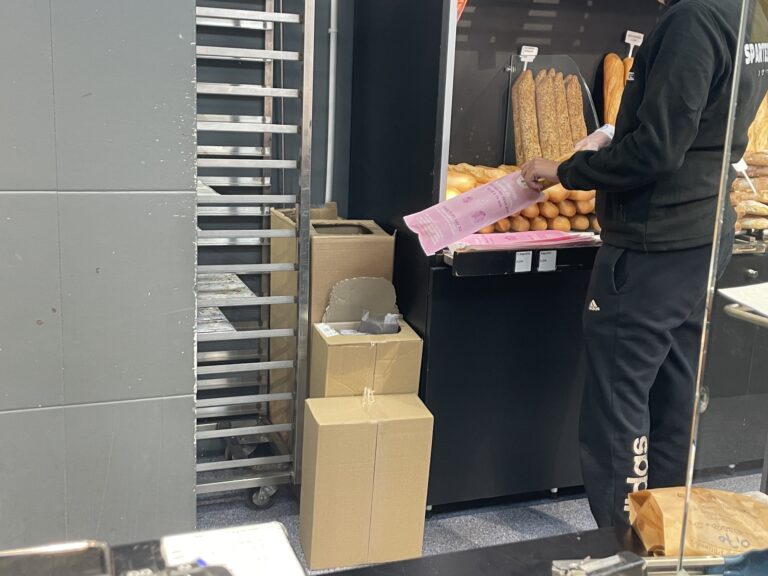 Mise en place des sacs à pain Octobre Rose derrière le comptoir d'une boulangerie